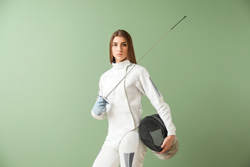 Young female fencer on color background