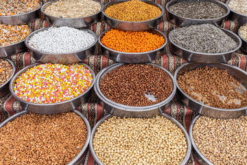 Assortment of different salted and sweet organic nuts and sunflower seeds in metal bowls standing on counter of street market. 