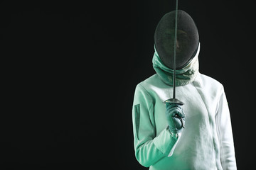 Young female fencer on dark background