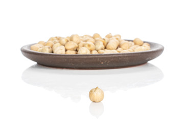 Lot of whole fresh tan chickpea one in focus with brown ceramic coaster isolated on white background