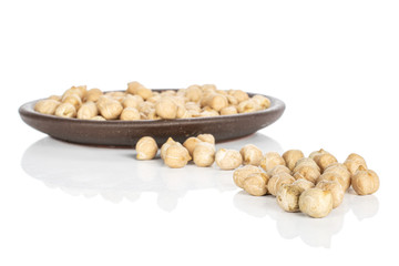 Lot of whole light fresh tan chickpea with brown ceramic coaster isolated on white background