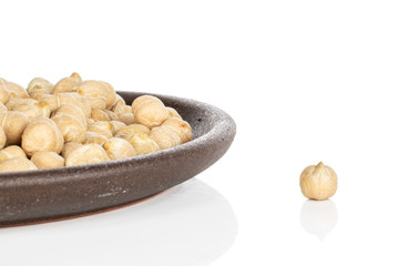 Lot of whole fresh tan chickpea with brown ceramic coaster isolated on white background