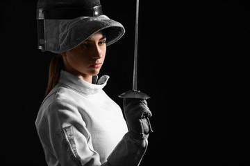 Young female fencer on dark background