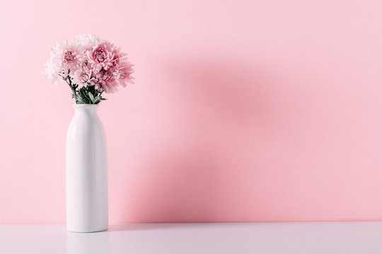 Fresh bouquet of pink flowers in vase on white shelf on pink wall background. Valentines Day, Easter, 8th march, Mother day background. Floral home decor.