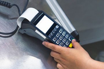 Male hand holds a bank terminal in hands at the cash desk, enters a password from a credit card