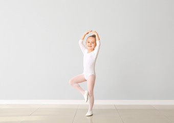 Cute little ballerina against light wall