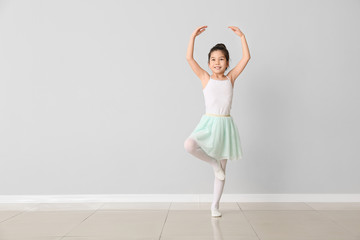Cute little ballerina against light wall