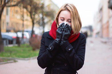A young woman blows her nose in a handkerchief, a new virus, seasonal colds. The girl suffers from...