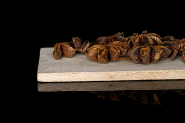 Lot of whole aromatic brown badian on wooden cutting board isolated on black glass