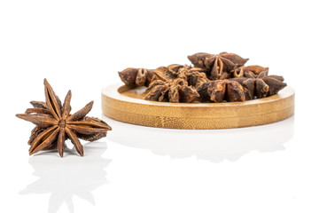 Lot of whole dry aromatic brown badian on round bamboo coaster isolated on white background