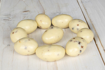 Group of ten whole coated white almond nut stracciatella on white wood