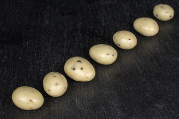 Group of seven whole coated white almond nut stracciatella on grey stone