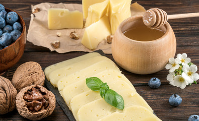 cheeses, honey and blueberries with nuts on a wooden background