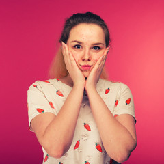 Portrait of teen girl touching her face and looking for acne
