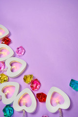 white hearts with light bulbs lie on a purple background with bright glass stones.Valentine's day.vertical picture   