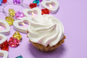 cake with white cream on a purple background.garland of hearts.multicolored glass stones. Valentine's day