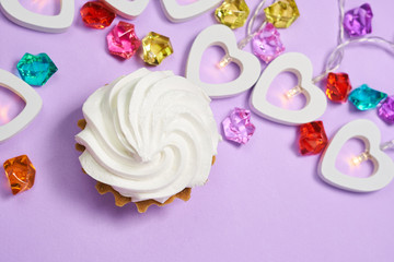 cake with white cream on a purple background.garland of hearts.multicolored glass stones. the view from the top.Valentine's day