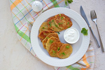Traditional potato pancakes made from raw potatoes on a white plate on a light background concrete. Belorussian cuisine. Potato Recipes. Served with sour cream.