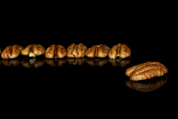 Lot of whole tasty brown pecan half in row isolated on black glass