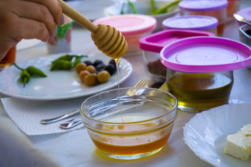 Female hand preparing honey to put on cream. Delicious breakfast ingredients.