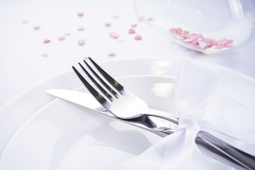 Sweet hearts in a glass with cutlery and a white ribbon on a white background, with place for text. Valentine's Day. Love concept.