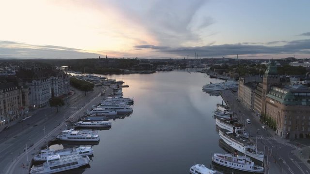 Stockholm Nybroviken small bay aerial view at dawn. Drone shot flying over water and ferry boats in small harbor. Capital city of Sweden, cityscape skyline, &Ouml;stermalm district