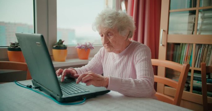Grandmotehr sitting in front of her laptop and browsing the internet
