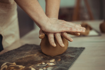 A man wrinkles clay with his hands. Work on the pottery wheel. The master is preparing clay.