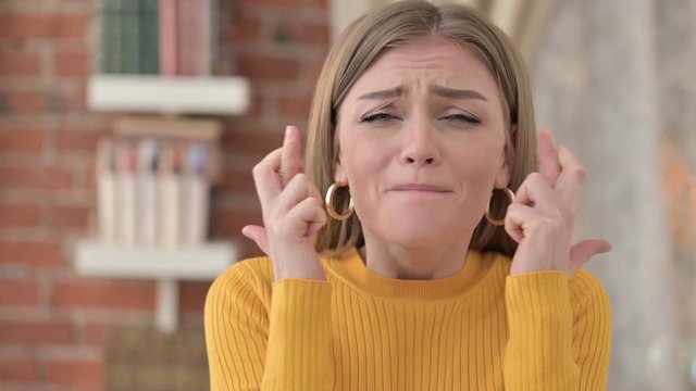 Portrait of Hopeful Young Female Praying with Fingers Crossed 