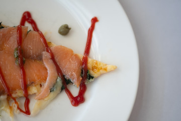 Piece of pizza salmon with ketchup ready to eat.