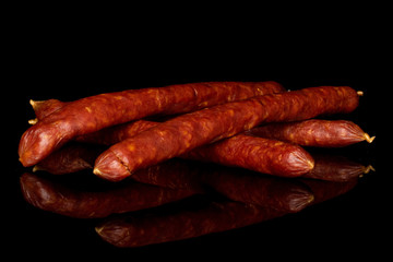 Group of four whole piquant smoked sausage isolated on black glass