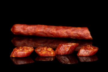 Group of one half four slices of piquant smoked sausage isolated on black glass