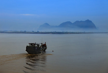 Obraz premium A boat is traveling to dramatic land through the river