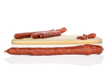 Group of two whole one half lot of slices of piquant smoked sausage on bamboo cutting board isolated on white background