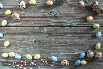 Easter holiday background. Frame of quail eggs and willow on old paint wooden background. Space for text