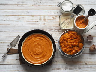 Round homemade pie with pumpkin. Stage of cooking. We spread the filling. Wooden background....
