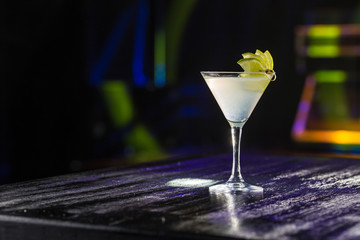 Margarita cocktail with lime slice on bar table on night club background