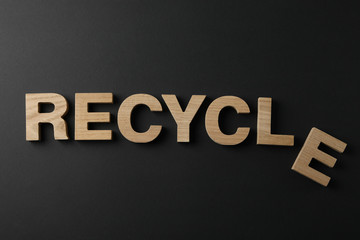 Word Recycle made of wooden letters on black background, top view