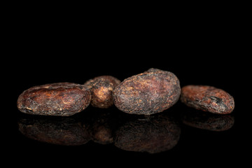Group of four whole fresh brown cocoa bean isolated on black glass