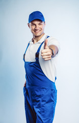Portrait of young worker man wearing blue uniform. Showing thumb up. Movement cool. Isolated on...