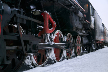 driving wheels of an old steam locomotive standing on rails in winter