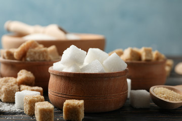 Bowls with different sugar on wooden background, close up