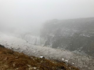 Breathtaking scenery at the Gullfoss Golden Waterfall landmark, a nature attraction in Iceland: Arctic nature with majestic rocks, the Hvita river running in the winter canyon with a cloudy white sky