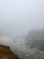 Breathtaking scenery at the Gullfoss Golden Waterfall landmark, a nature attraction in Iceland: Arctic nature with majestic rocks, the Hvita river running in the winter canyon with a cloudy white sky
