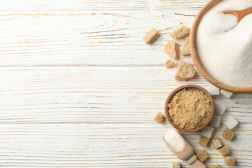 Bowls with sugar on white wooden background, top view