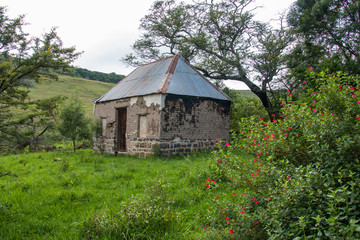 Fototapeta na wymiar Abandoned Tumbledown Ruins, Buildings With Bright Coloured Plants In The Drakensberg Mountains, South Africa