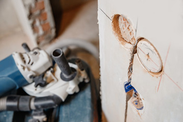 Builder man cutting electrical chase in concrete wall with circulation saw drill diamond crown