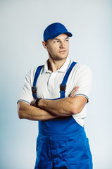 Portrait of young worker man wearing blue uniform with crossing hands. Isolated on grey background...