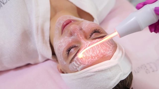 Receiving electric darsonval facial massage procedure.