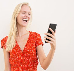 Naklejka premium attractive blonde woman laughing whilst using her phone.